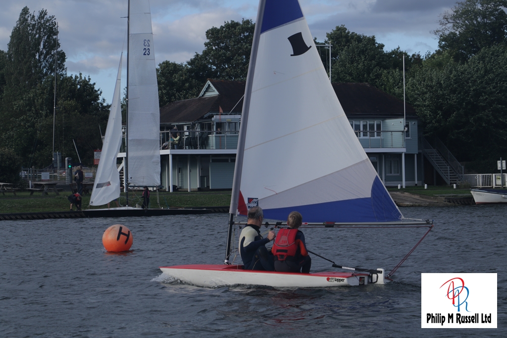 A small dinghy with a red top, a club toppercruising on the river Thames
