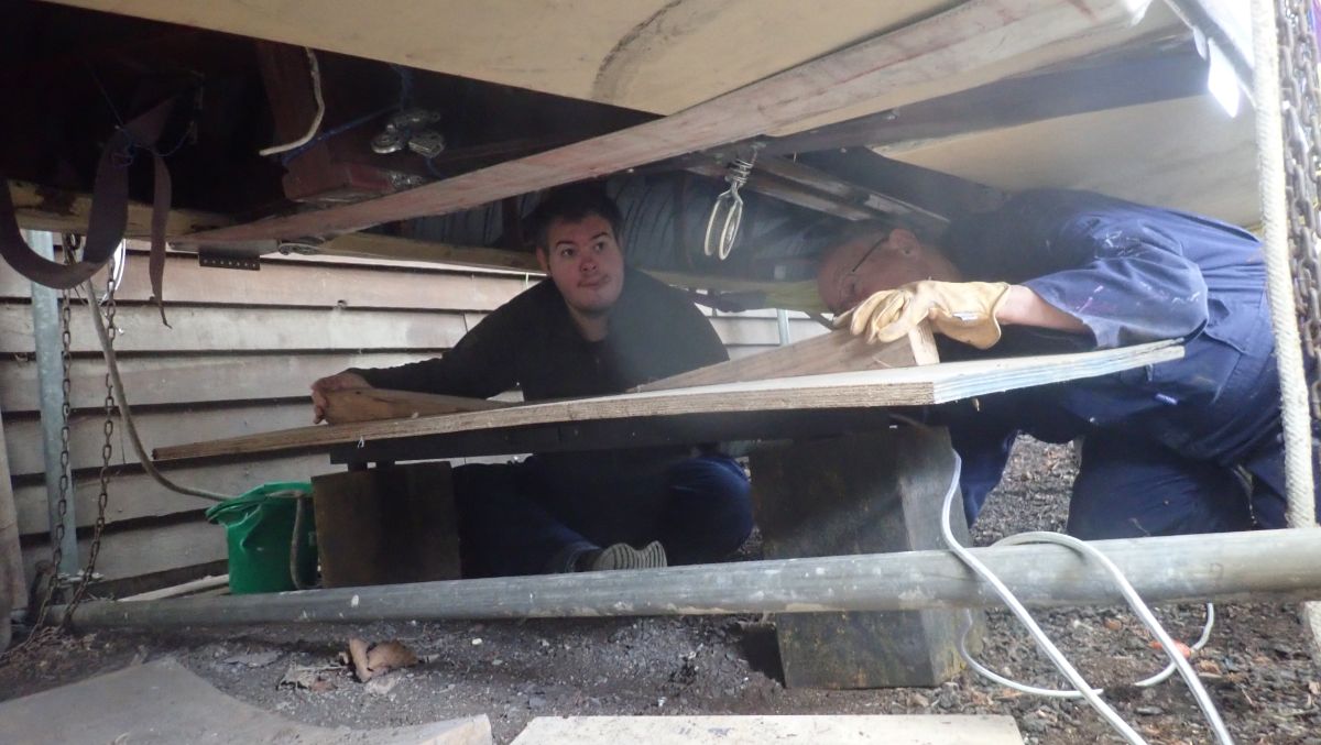 Paul and Guy under Daity Twoo placing Wedges under the boat to support it