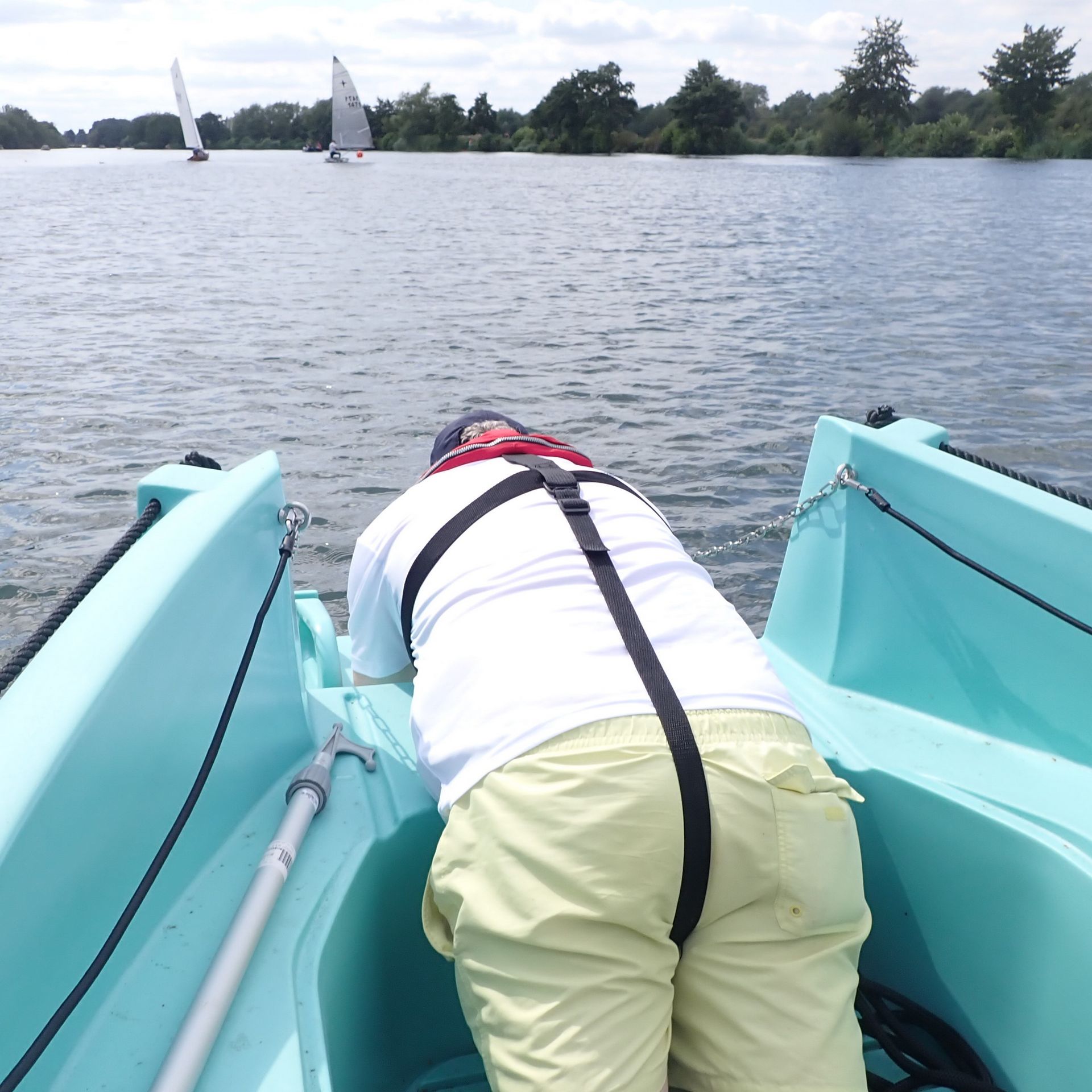 The bow down in the boat and leaning out to get a low angle shot of the sailing boats passing by.